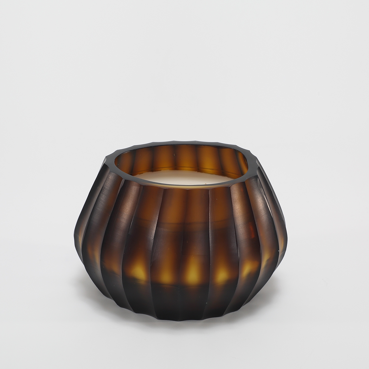 Aura Amber Candle burning, releasing Volcanic Embers fragrance in hand-carved glass vessel