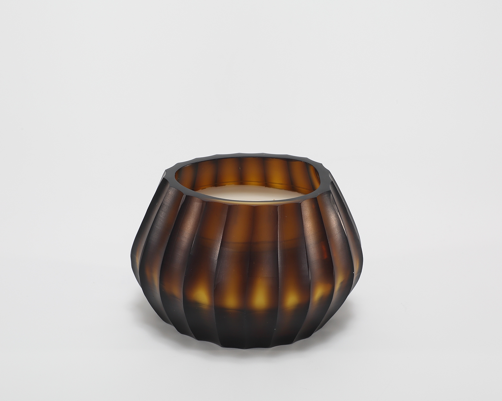 Aura Amber Candle burning, releasing Volcanic Embers fragrance in hand-carved glass vessel