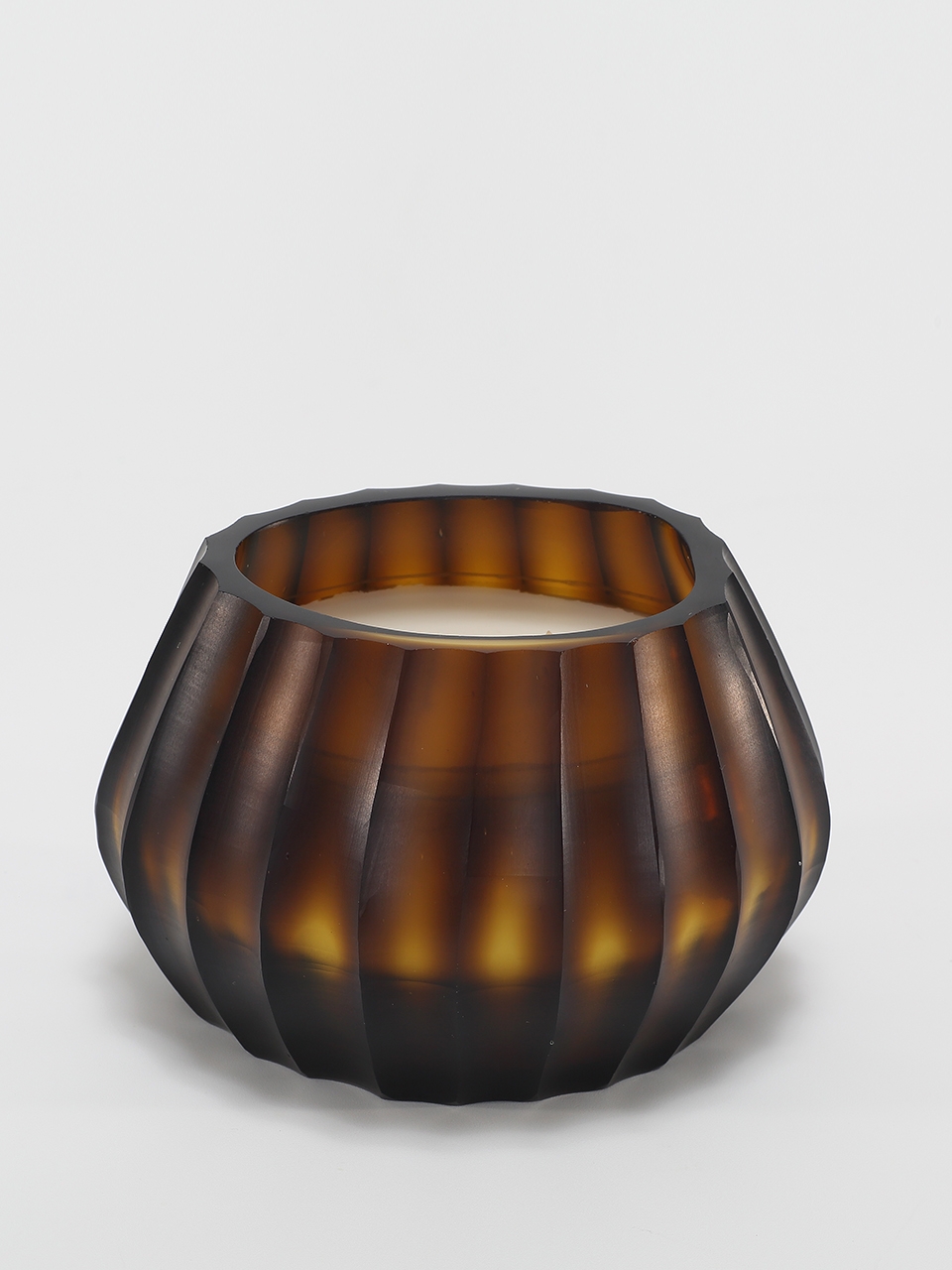 Aura Amber Candle burning, releasing Volcanic Embers fragrance in hand-carved glass vessel