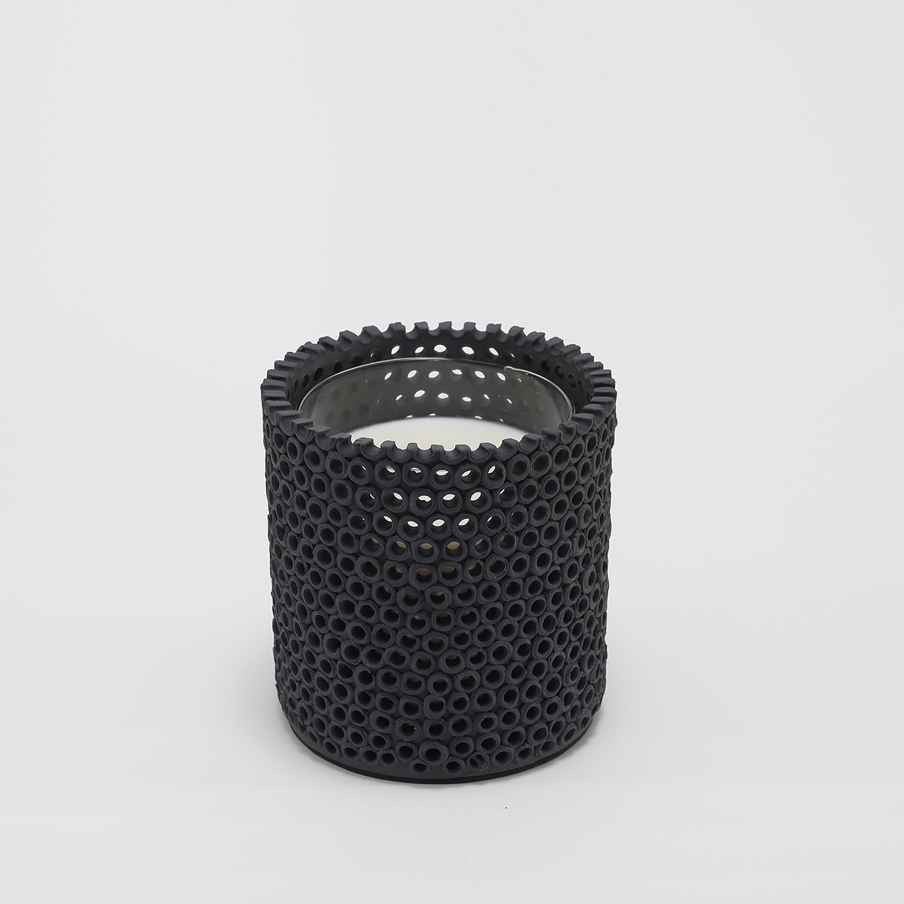 Coralite Ebony Candle burning, releasing Noir fragrance in handmade ceramic vessel
