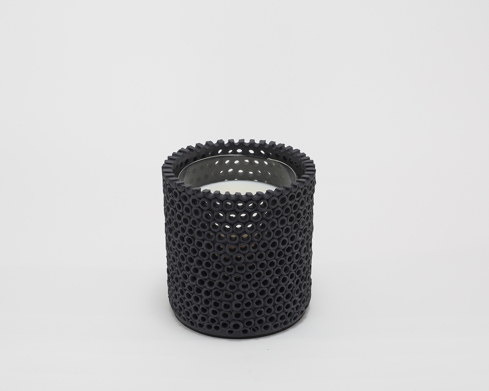 Coralite Ebony Candle burning, releasing Noir fragrance in handmade ceramic vessel