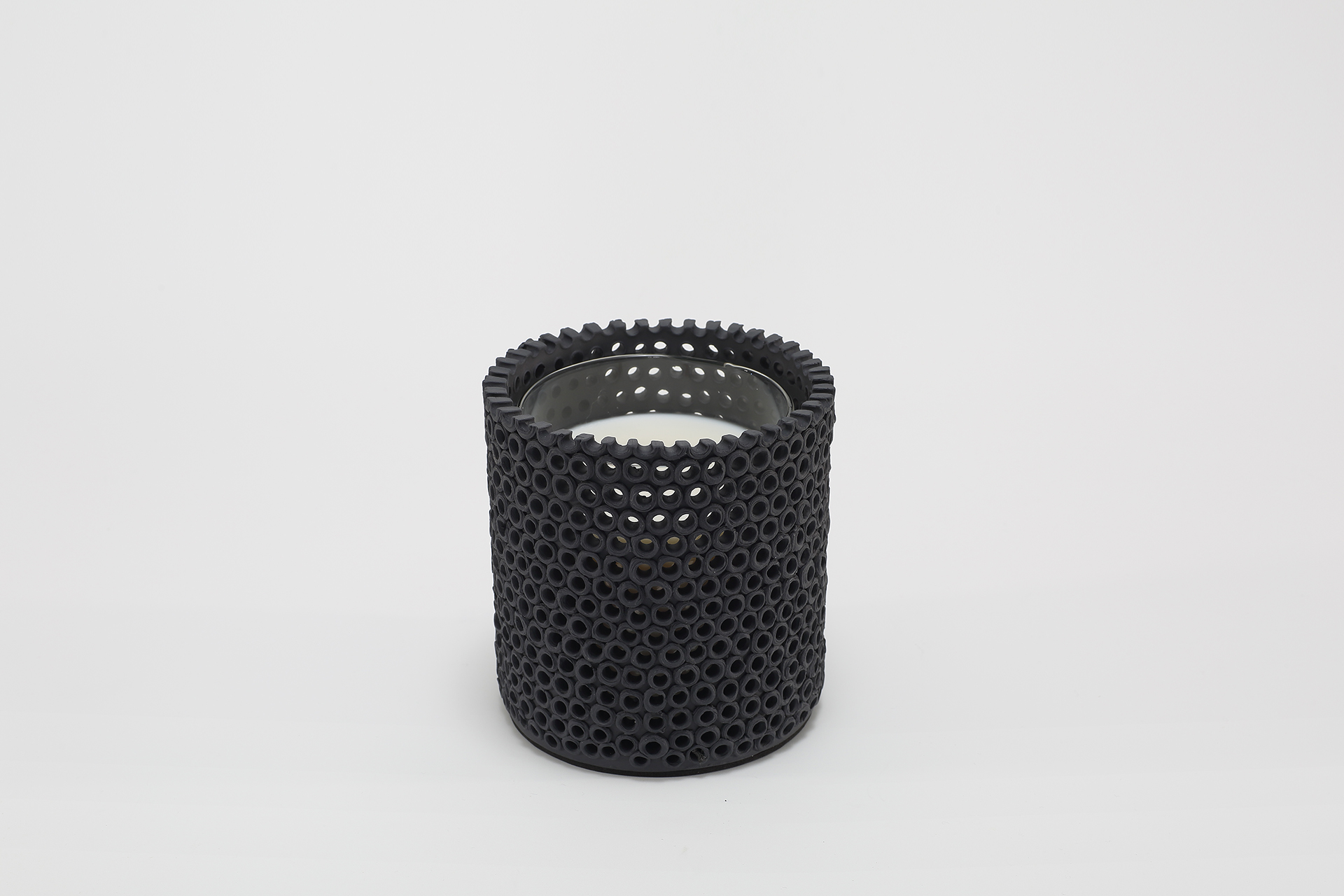 Coralite Ebony Candle burning, releasing Noir fragrance in handmade ceramic vessel