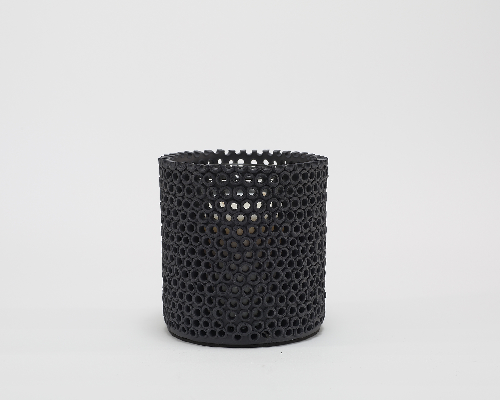 Coralite Ebony Candle burning, releasing Noir fragrance in handmade ceramic vessel