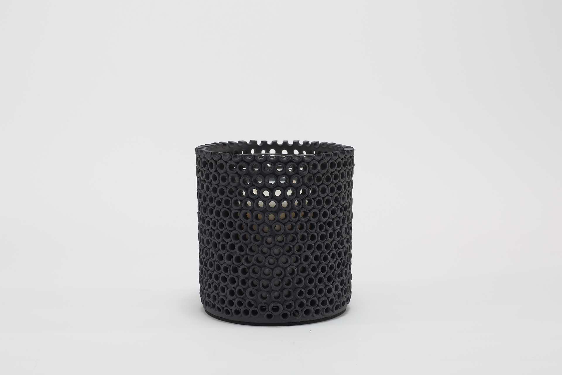 Coralite Ebony Candle burning, releasing Noir fragrance in handmade ceramic vessel